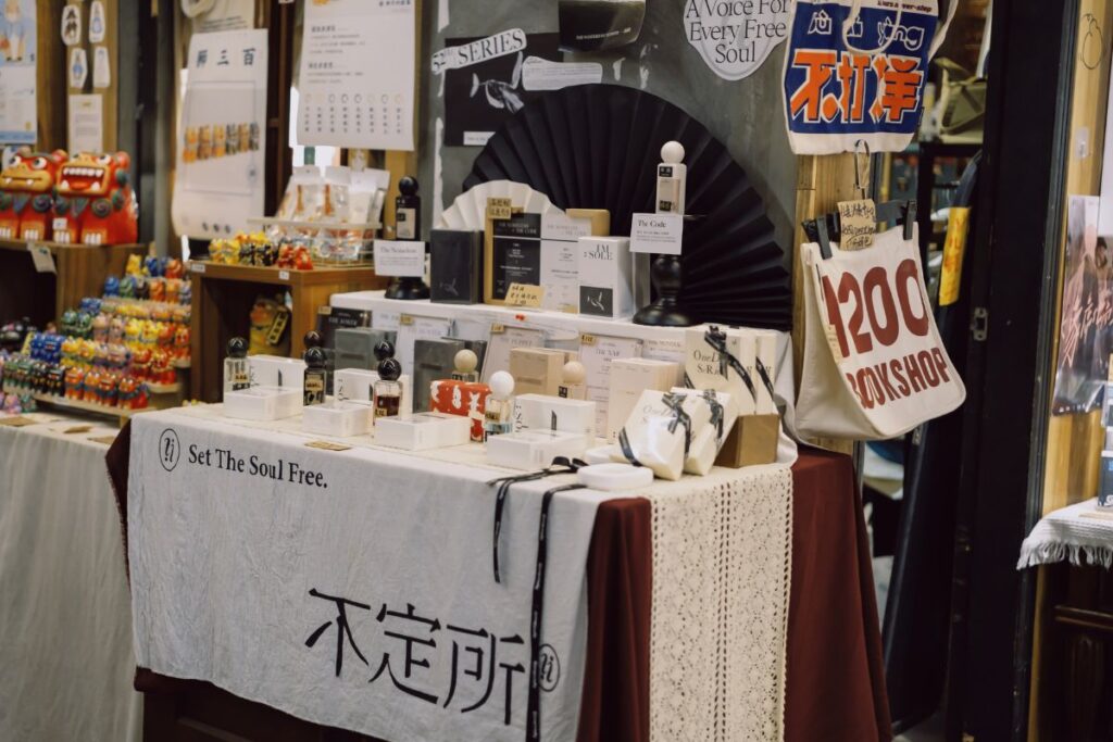 Uma mesa de exibição em uma loja ou mercado com perfumes e outros produtos de beleza em embalagens elegantes, com texto asiático.