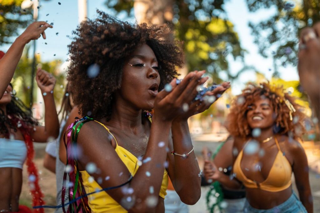 Foliões jogando confete durante bloco de carnaval nas ruas do Rio de Janeiro na maior festa popular do Brasil