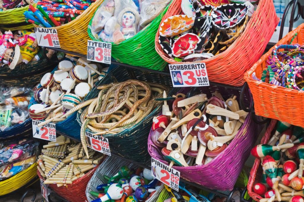 Cestas coloridas cheias de diversos itens de artesanato local para turistas, incluindo flautas, bonecos e outros produtos feitos à mão.