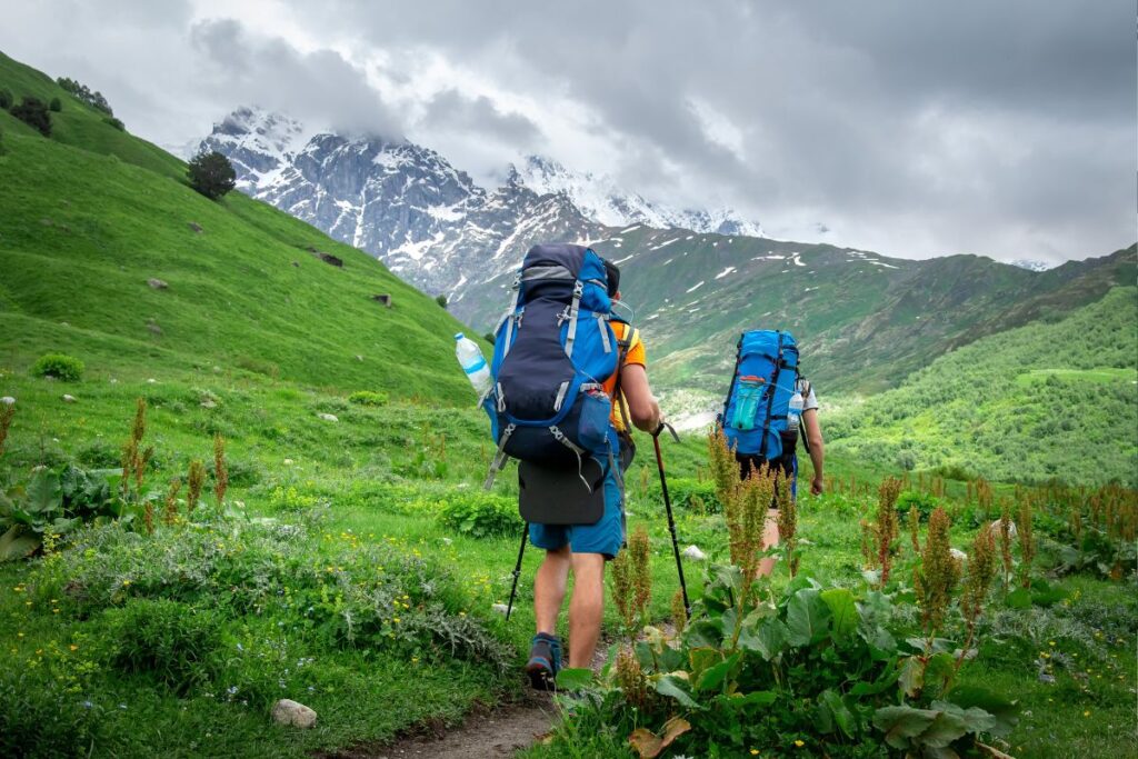 Aventureiros fazendo trekking com mochilas em trilha de montanha, esporte de caminhada descoberto viajando pelos Alpes