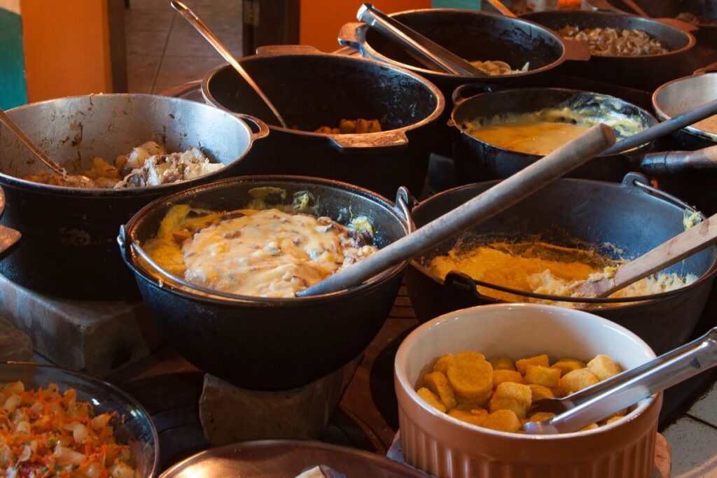 Buffet de comida típica mineira com pratos servidos em panelas de ferro sobre fogão à lenha