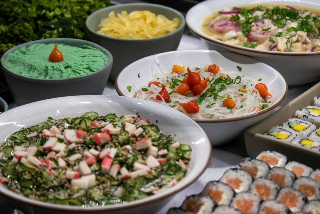Uma variedade de ceviches e sushi em uma mesa de buffet.