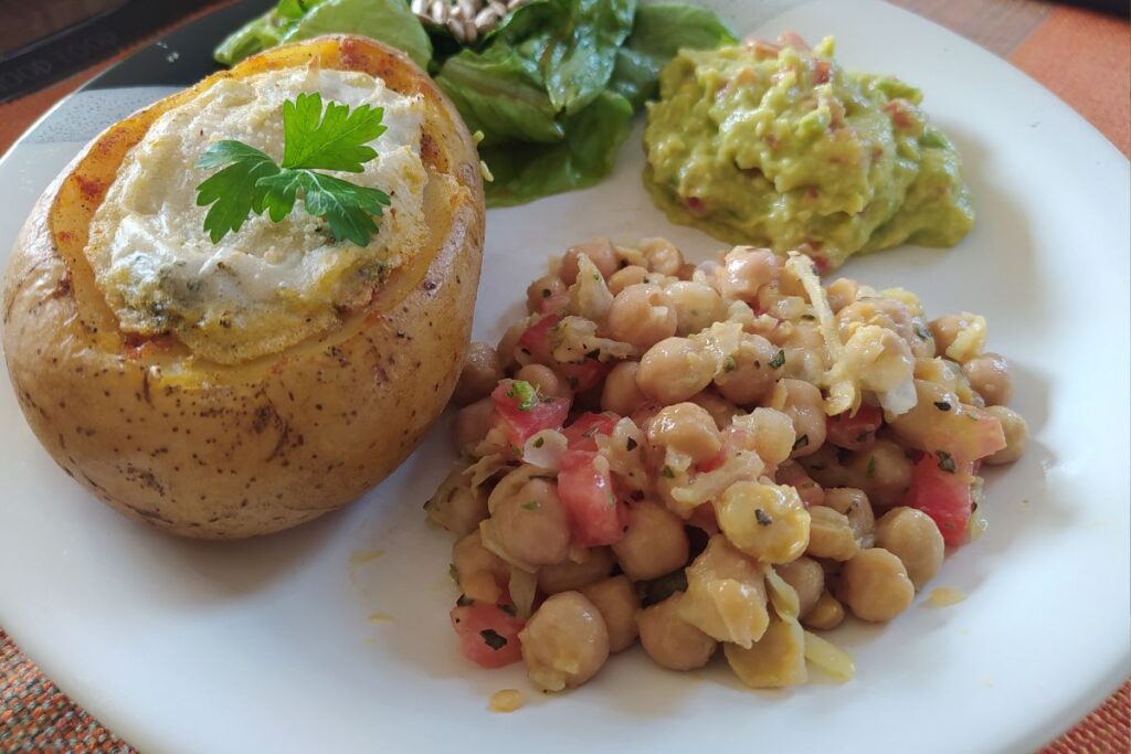 Batata recheada, salada de grão de bico e guacamole em um prato.