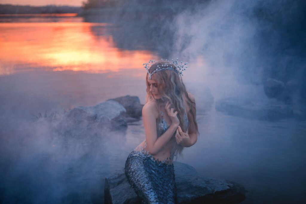 Figura mística inspirada na lenda da Iara às margens de um rio da Floresta Amazônica, envolta em névoa e luz suave ao entardecer.